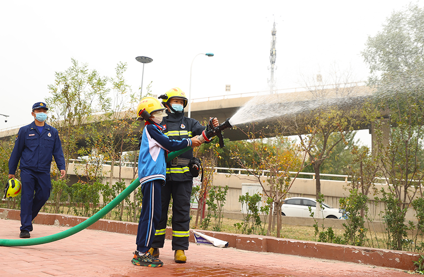 消防員為學生現場演示如何使用消防裝備器材。天津市紅橋區委宣傳部供圖