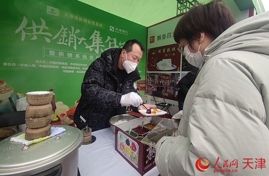 市民在年货节“民俗广场”购买品尝天津特色小吃。人民网 孙一凡摄