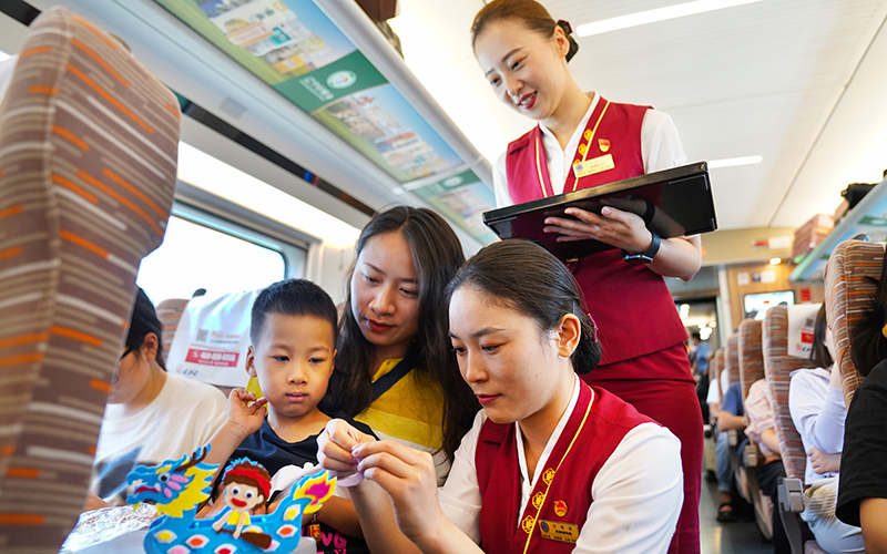 6月22日，G305次列車乘務人員幫助小旅客制作龍舟手工。劉超攝
