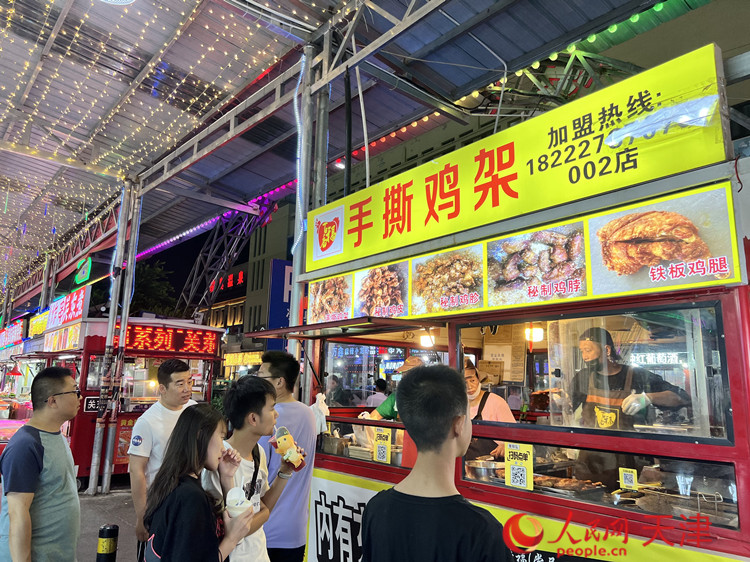 王国栋一边熟练地炸着鸡架，一边亲切地和顾客交谈。 人民网记者 孙翼飞摄
