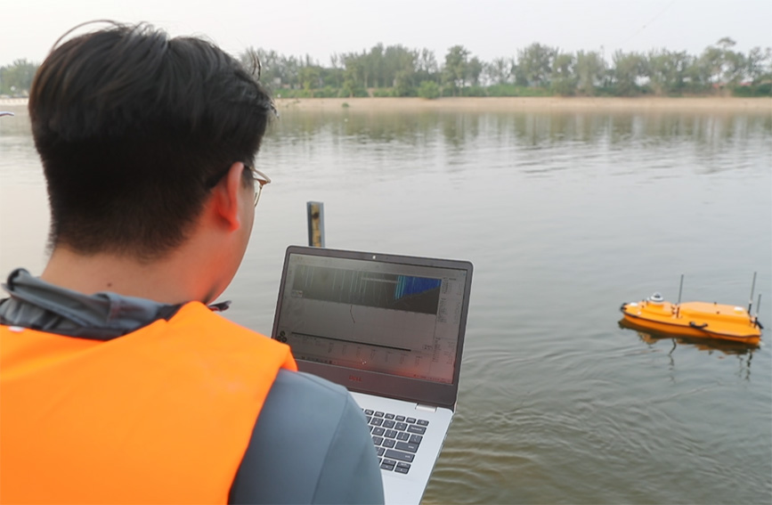 水文人员在岸边使用水文智能无人船进行水文监测。独流减河进洪闸管理处供图