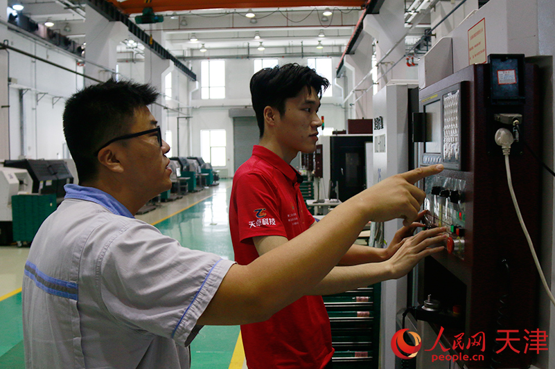 中國（天津）職業技能公共實訓中心實訓車間裡，王傳龍（左一）正在輔導學員操作機床。    人民網記者 陶建攝