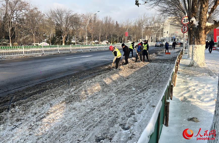 友谊路上，相关人员正在铲除道路两侧积雪。人民网记者 张静淇摄