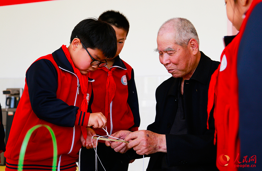 郝同丰在教小学生们制作盒子花。人民网记者 崔新耀摄