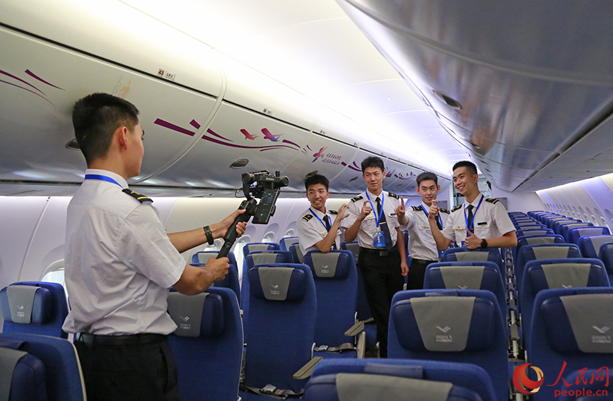 中國民航大學飛行技術專業學生在飛機客艙內比出“C919”的手勢。人民網記者 崔新耀攝