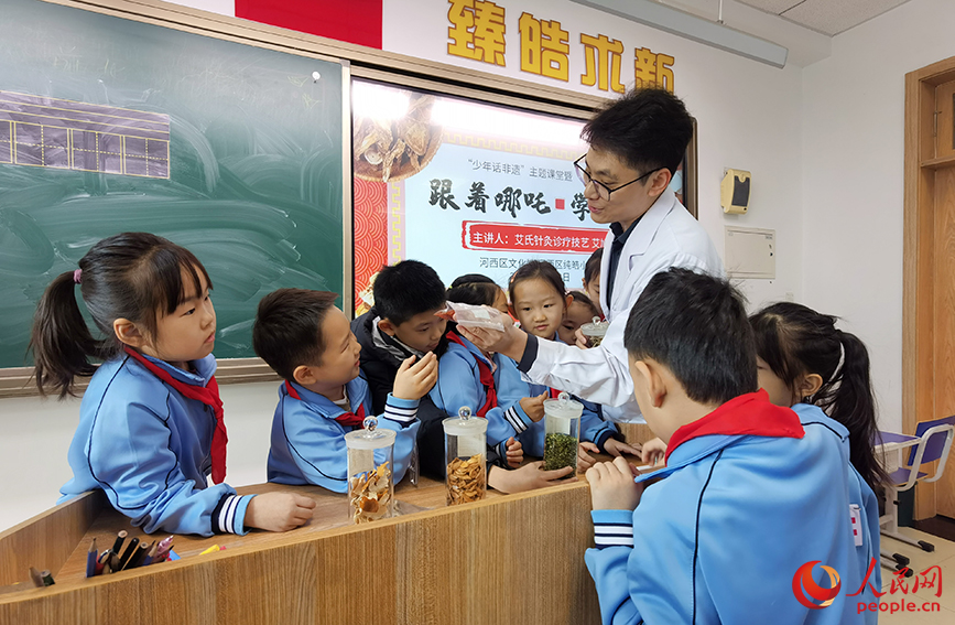 艾氏针灸诊疗技艺传承人艾旭拿出真实的药材展示给同学们。人民网记者 陶建摄