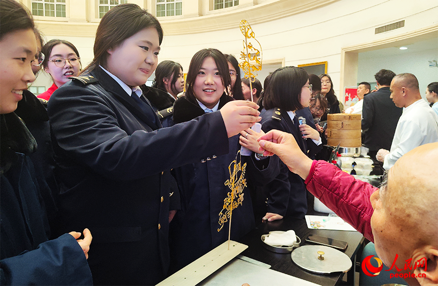 学生接过津门戈氏鱼虫糖艺传承人制作的糖画。人民网 郭维瑾摄