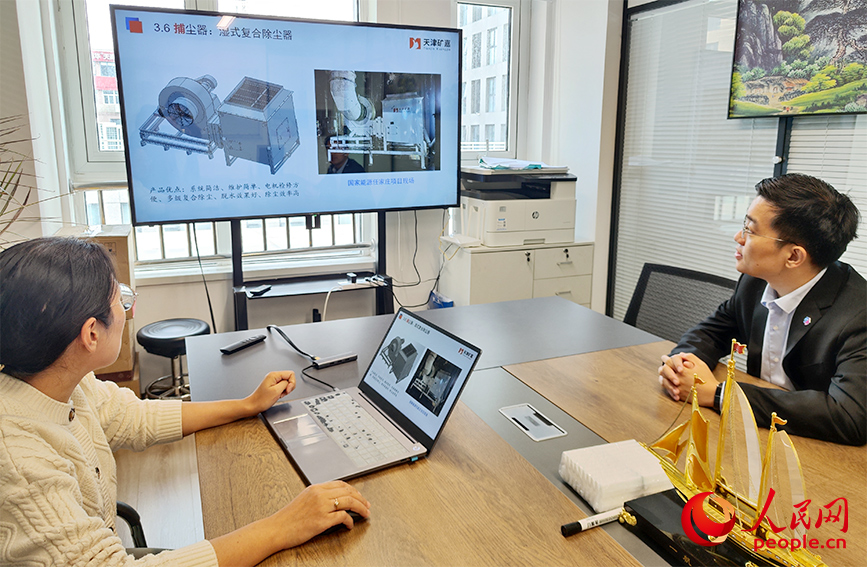 天津礦嘉工程科技有限公司副總工程師任利勤（左一）向遲恆烜介紹企業最新投產的設備。人民網記者 郭維瑾攝