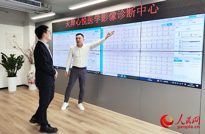 天津心悅醫學影像診斷有限公司總經理閆銘（右一）向遲恆烜展示遠程心電監測服務產品的技術優勢。人民網記者 郭維瑾攝
