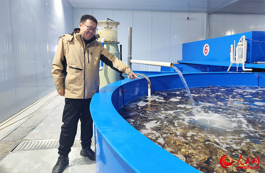 邊建偉介紹暫養池的水溫和鹽度。人民網記者 郭維瑾攝