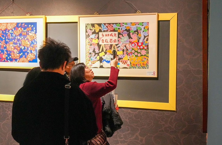 參觀者在農民畫作品前拍照打卡。活動方供圖