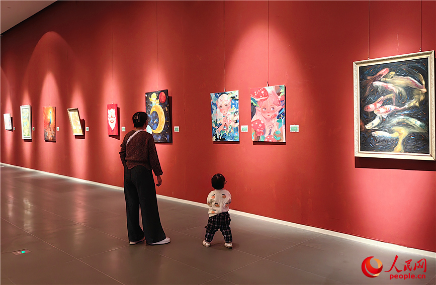 一位小朋友在家长的陪伴下，专注地观看画中的人物。人民网记者 李丹摄