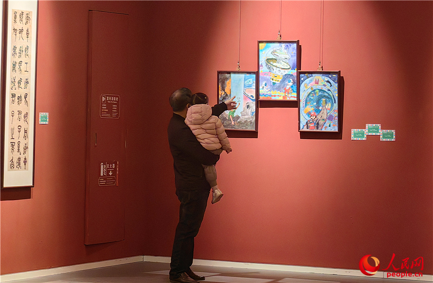 一位家长正耐心地为孩子讲解画作中的故事与人物形象。人民网记者 李丹摄