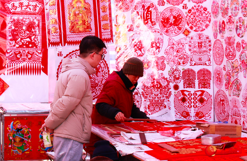 攤主為游客展示吊錢樣式。人民網記者 唐心怡攝