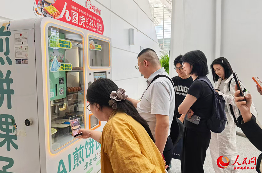 2026世界智能產(chǎn)業(yè)博覽會(huì)上，煎餅馃子機(jī)器人前，排起了長(zhǎng)隊(duì)。人民網(wǎng)記者 陶建攝