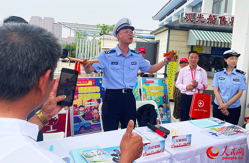 天津市公安局、交管总队摊位前，群众认真听快板学安全知识。人民网记者 唐心怡摄