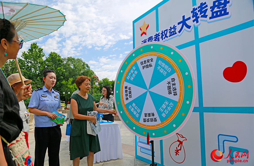 众人参与反诈主题大转盘趣味游戏。人民网记者 崔新耀摄
