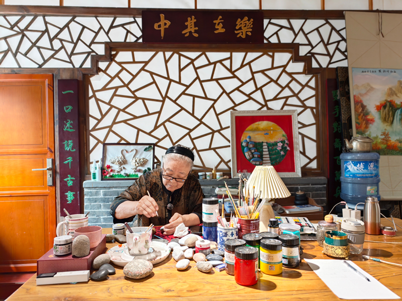 刘姥姥伏案创作石头画。 李家鼎摄