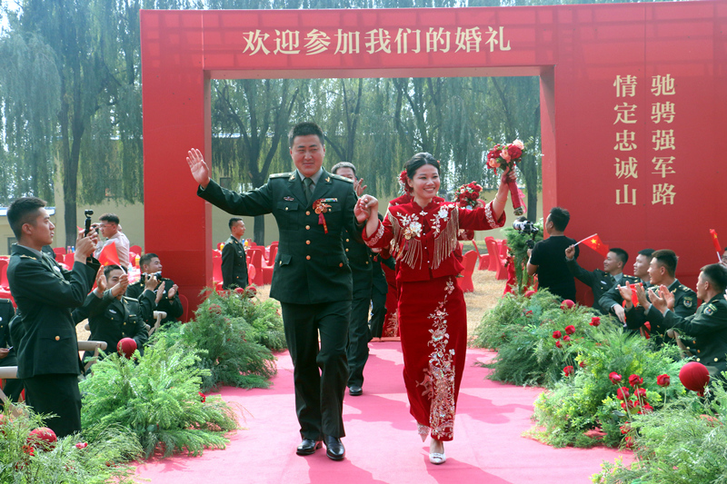 新人牽手走過婚禮拱門,在戰友熱烈掌聲中登場。王良攝